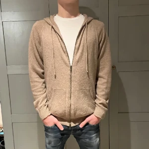 Kashmir zip hoodie - Davida kashmir / Cashmere zip hoodie i 100% kashmir. Färgen beige i storlek M. Tröjan e i bra skick (se bild 3). Box och lappar finns.