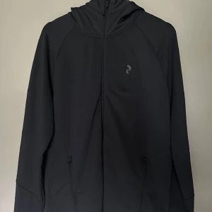 Peak performance  - Rider Mid Zip Hood från peak performance köpt för 1599kr. Använd men har inga defekter mer än att de vita bokstäverna och loggan har ramlat av vilket syns på bilderna. 