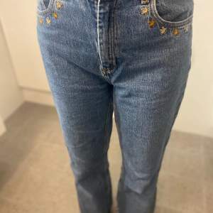 Jeans med broderade blommor vid farm fickorna. Storlek 38