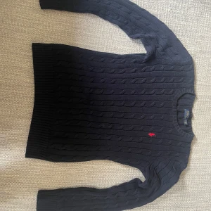 Ralph lauren tröja kabelstickad - As snygg kabelstickad Ralph lauren tröja i färgen mörkblå med röd logga. Tröjan är i mycket fint skick och det finns inga defekter. Säljer pga att den är lite för liten.