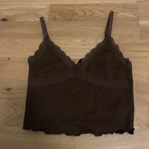 Brunt linne med spets - Litet brunt linne. Jätte gulligt men kommer tyvärr inte till användning längre. V-ringad och väldigt fin passform. Den har tyvärr gått upp lite vid ryggen men det märks inte när man har på tröjan och lätt att sy ihop om man vill.🤎