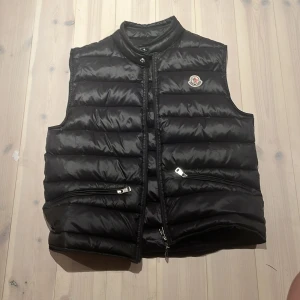 Moncler väst - Tja! Säljer en riktigt fet Moncler väst i storlek 1 i Moncler väst så S i vuxen. Den är köpt på Moncler för ett år sedan och är ganska bra skick bara att det är ett lite hål som är fixat med ett annat tyg som du ser i 4 bilden. Skriv om ni undrar nåt