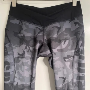 MM Sports träningstights M - Camo-mönstrade träningstights grå/svart, låg midja. Stl M (liten storlek) Diskret lagad (se bild)  Stor utrensning dam, barn och herr. Kika gärna på mina övriga annonser, köp bundle, få rabatt och betala bara för en frakt. Djur- och rökfritt hem.