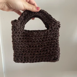 Virkad väska - Väska virkad i bomullsgarn. Längd: 18 cm Höjd: 12 cm (om man möter med handtagen är den 20 cm hög.)