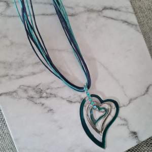 Fint halsband med hjärtan och stenar. Okänt material, inga märkningar. Fint skick. Det yttre hjärtat som är mer grönt i färgen, mäter ca 5,5x4,5 cm.