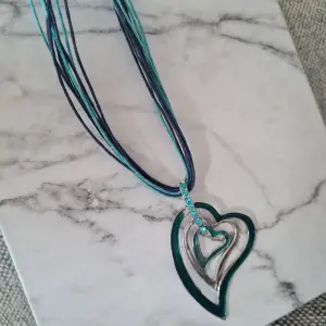 Fint halsband med hjärtan och stenar. Okänt material, inga märkningar. Fint skick. Det yttre hjärtat som är mer grönt i färgen, mäter ca 5,5x4,5 cm.