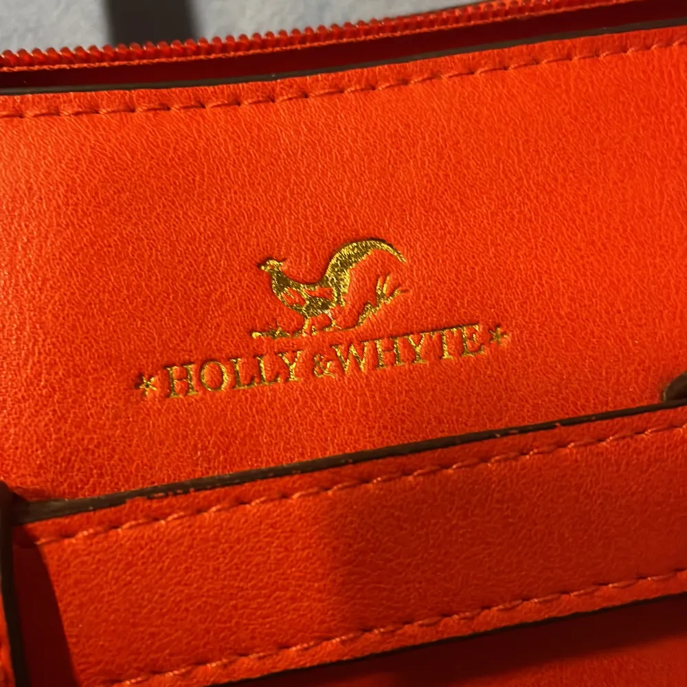 Röd väska från Holly and Whyte med guldiga detaljer  Något litet märke på den men inget som märks . Väskor.