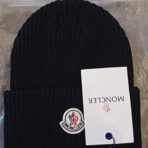 Moncler Mössa - Stilig svart mössa. Denna mössa kan kan aldrig vara fel att ha på sig!