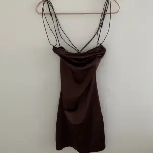 En metallic brun miniklänning med öppen rygg/flätad rygg. Underkläder med kanter är syndliga genom klänningen. Mycket bra skick. 