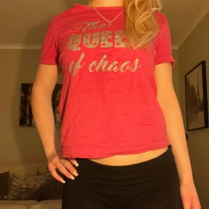 Rosa t-shirt - Säljer denna snygga, cola, rosa t-shirten som har silvrig text med ”The Queen of chaos” och kommer ej till användning💗den sitter ganska tajt och därför ger snygg form! Knappt använd.