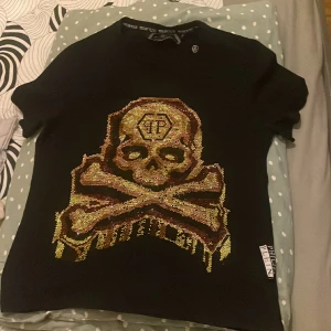 Philipp Plein T-shirt  - Säljer denna Philipp Plein T-shirt som lyser mycket vid ljus. Fick den som present för ett tag sen och har tyvärr ingen kvittodetalj då det var en gåva, men är ganska säker på att den köptes på NK i Stockholm.
