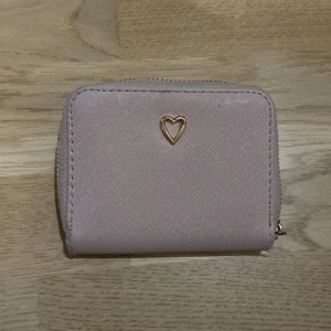 Baby rosa plånbok - Har använt lite och har försökt klippa bort lappen inuti, jätte fin och okej skick. Den är baby rosa färg och har bra med utrymme för kort och kontanter.