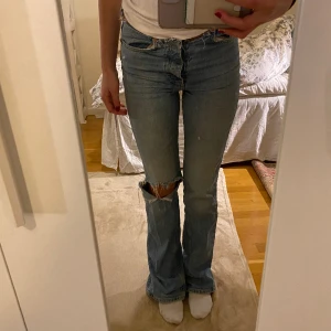 Midwaist flare jeans  - Midja(tvärs över):38 cm Innerbenslängd: 83 cm Medelhög midja med hårt jeansmaterial, en liten slits där bak längst ner på jeansen. Hål på knät. Bra skick.
