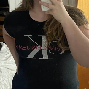 Svart Calvin klein jeans tshirt - Svart tshirt från calvin klein med gemstones / diamanter och rosa text, passar L-M också 