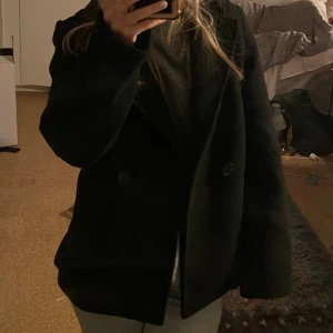 Kappa  - Säljer denna svarta kappa i kortare modell. Har endast använt den ett fåtal gånger, och säljer då jag har en annan liknande. Den är i storlek XS, men skulle säga att den passar S också. Kan skicka fler bilder vid intresse!