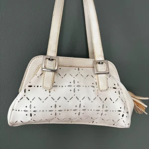 Handväska  - A vintage geometric style women hand bag in off white. Perfect size for daily use and lots of room for phone, keys, make up and wallet. There are some minor discolouration hence the low price. The bag exterior is faux leather