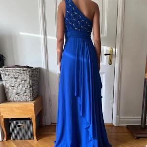 Långklänning - Långklänning i electric blue, använd två gånger. Fint skick. Strass inflätat upptill. Matchande sjal medföljer. 