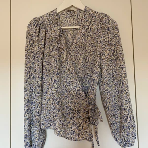 Blommig omlottblus - Blommig omlottblus i storlek 36 från Only. Knyts vid midjan 