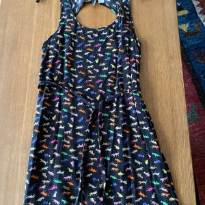 Svart klänning med mönster/kattdjur i många färger.  - Svart klänning med mönster/kattdjur i många färger.  Knytskärp och rundad öppning upptill i ryggen.  HM,  St. 36. Bomull, viskos  