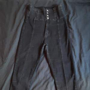 Svarta skinny-jeans i stretchigt tyg och JÄTTEHÖG midja. Snygga knappar på framsidan, inga framfickor men har bakfickor. 