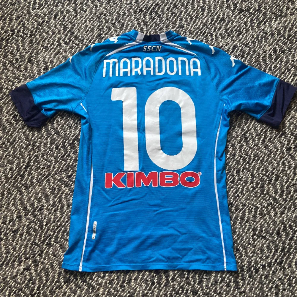 Napolis hemmatröja från 20/21 säsongen med Diego Armando Maradona på ryggen. Den säsongen han tyvärr gick bort. Använd men fortfarande i bra skick Skick: 8,5/10 Storlek: Medium (sitter som S) Kontakta gärna angående frågor och liknande. T-shirts.