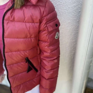 Moncler jacka/ röd ,rosa  - Aldrig använd moncler jacka som jag säljer då den inte passar mig och inte gör nån användning hemma. Den är äkta och köpte den här på Plick, pirs kan diskuteras.