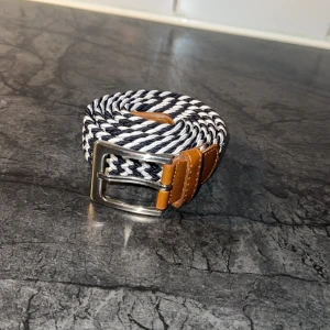 Flätat bälte  - Tjena! Säljer ett riktigt stiligt flätat bälte i en riktigt snygg randig färg skick 10-10