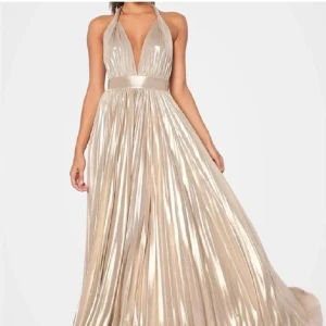 Balklänning  - Champagne färgad balklänning med öppen rygg. Skulle säga att den passar S-M då man kan knyta den där bak. Den är metallic. Original priset är 1599kr,säljer för 1200. Pris kan diskuteras.