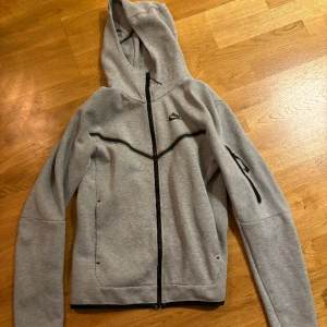 Nike tech fleece grå - Den är 2 år gammal och använd men fortfarande i hyfsat bra skick. Storlek XS. Den är köpt från Nikes officiella butik.
