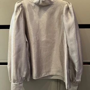 Sammie blouse STOCKHOLM   - Lyxig blus i skimrande creppat tyg. Skimrar i guld/silver. Fodrat med ett innerlinne. Aldrig använd, prislapp kvar. Nypris 699:-