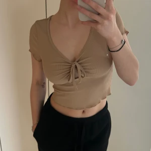 Fin topp - En fin beige topp med knytning fram till i ett ribbat material.