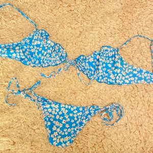 Blå bikini  - En söt blå bikini med vita blommor. Till personen som älskar att sticka ut med en stark & somrig färg på stranden 😍👙🐬