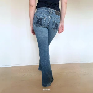 Lågmidjade Vintage Bootcut Jeans  - Mer info och möjlighet att köpa plagget finns på vår hemsida 😊  MODELL: Lågmidjade & Bootcut. FÄRG: Blå. STORLEK: 28 enligt lapp. Uppskattad storlek 34. MIDJA RAKT ÖVER: 37 cm.