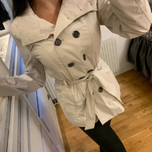 NY Beige kort kappa - Ljusbeige kappa från Mexx. Otroligt fin men aldrig kommit till användning. Det finns även en knapp som gör att den sitter tightare vid midjan. Skulle säga att den passar Xs-S. Nypris är 1299kr.