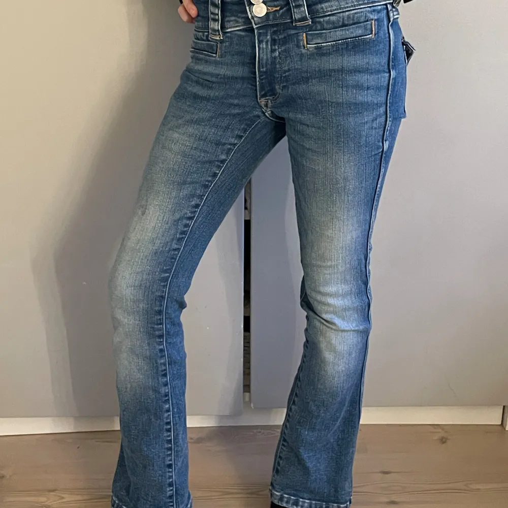 Blåa lågmidjade jeans med två knappar där fram, och fickor med knappar där bak, bootcut jeans, går att spänna in jeansen!. Jeans & Byxor.