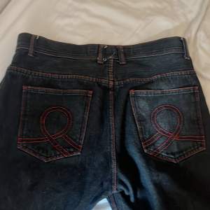 Jätte snygga mörkblå straight leg jeans med röda sömmar och detaljer på fickorna. Hål i framfickorna men annars i bra skick. ca 100cm långa. 