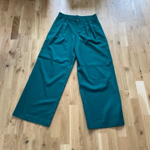 Gröna kostymbyxor  - Säljer mina gröna vida kostymbyxor från H&M då de är för långa för mig. Aldrig använda och därför i nyskick. Säljs för 200 kr. 
