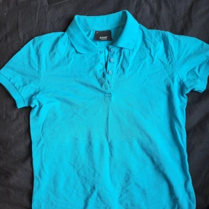 Blå polo skjorta - Aldrig använd polo-skjorta som bara ligger i skåpet. Är i nyskick och materialet är jätte nice för sommarväder :) 