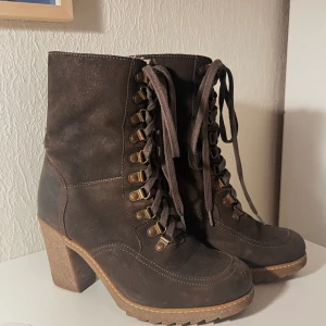 Kängor med klack - Ett par fina bruna mocka/läder-kängor med klack, de är fodrade och stängs med snörning. Ena skon är lite skavd längst från på tån. Stl. 39 