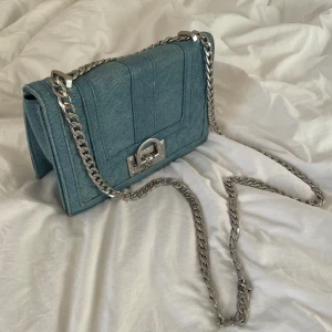 Axelremsväska  - Fin väska i jeans från Gina tricot🤍 Finns ej kvar längre. Kedja som man han justera så den antingen bärs på ena axeln eller som en axelremsväska. Lämna prisförslag❣️❣️