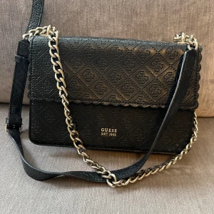 Guess väska  - Axelremsväska från Guess i silver och reglerbart band. Använd med fortfarande i fint skick. 