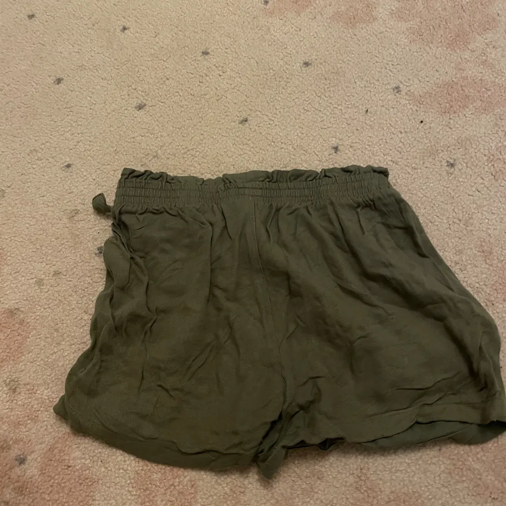 Ett par olivgröna shorts som jag har använt dem mycket med de är fortfarande i väldigt bra skick de är bara lite skrynkliga men det kan man styka om man vill de är väldigt sladriga vilket jag tycker är skönt för det sitter inte stelt på kroppen . Shorts.