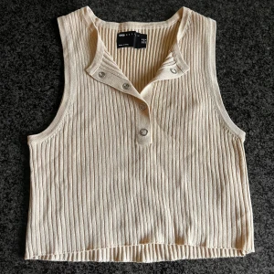 Beige topp - En beige kortare topp som kan knäppas i urringningen  Storleken är EUR 38