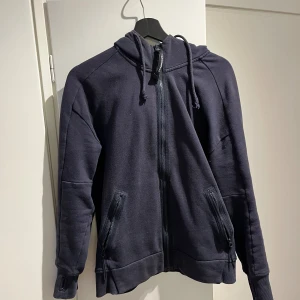 cp company hoodie - Säljer denna cp company hoodie då den blivit för liten. Ganska bra skick 8/10 storlek small. Säljer den för 500kr (står ej för frakt) det är dock ett hål i armhålan, därav det billiga priset.  