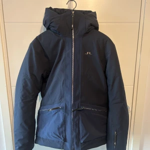 Skidjacka J.Lindeberg - En grym skidjacka som aldrig kom till användning pga skada. Den är sprillans och har aldrig använt i backen. Stilren, varm och vattenavstötande. Den sitter som en klassisk medium!  Vid smidig affär kan jag gå ner nån hundralapp! 