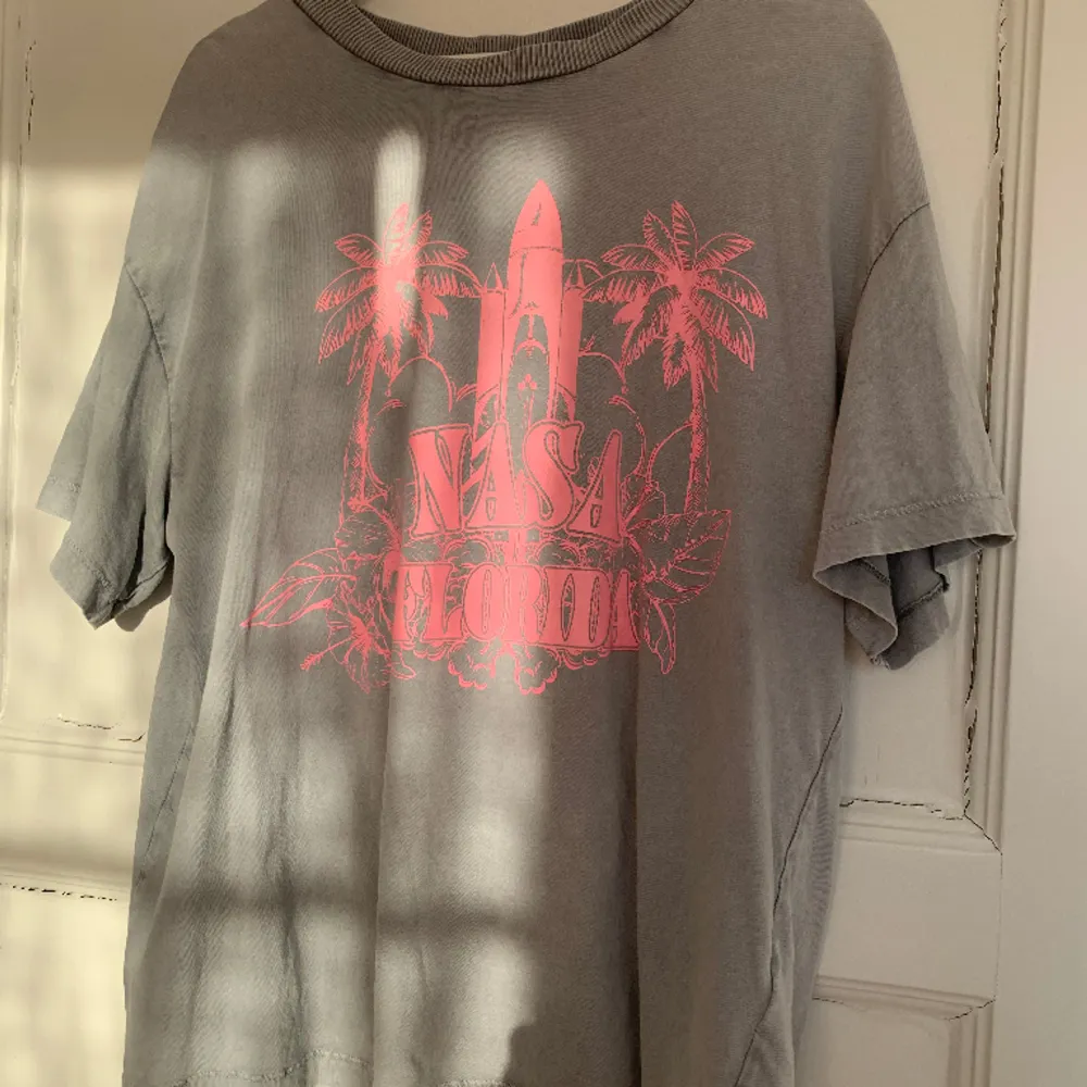 En oversized T-shirt från H&M i storlek S (sitter mer som L). Ljusgrå med neonrosa tryck. Har inga hål eller fläckar. . T-shirts.
