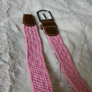 Rosa bälte nytt  - Ett rosa  bälte med ett silverspänne. Bältet är vävt och har en läderflik på båda sidorna. Längd 107,5. Kolla gärna in mina andra annonser då jag säljer samma skärp fast i olika färger