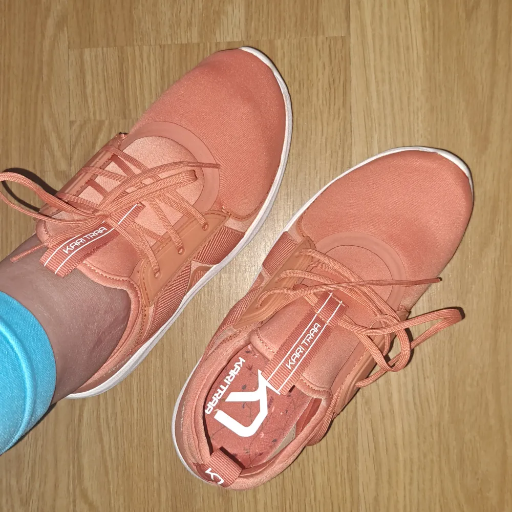 Ett par orange (coral) sneakers från Kari Traa med snörning och vit sula. Skorna har en sportig design och är bekväma för vardagsbruk. storlek 36. Från stadium. Och bär 1 gång bara. . Skor.