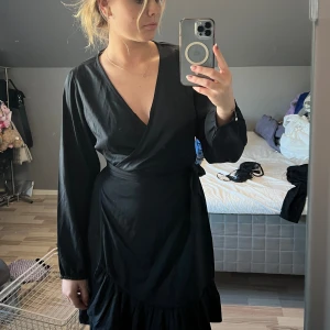 Klänning  - Svart omlott klänning som går att knyta på olika sätt. Enbart använd vid ett tillfälle så är som ny
