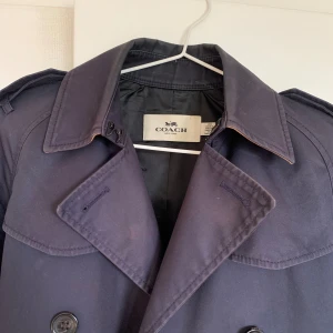 Marinblå trenchcoat  - Marinblå kort trenchcoat från Coach! Storlek XXS, men passar även XS och förmodligen en liten S!